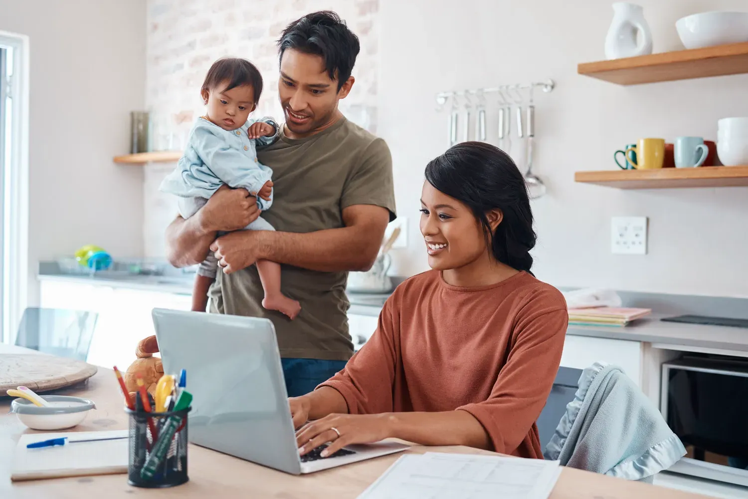 Smiling family at home reviewing finances on a laptop, representing smart alternatives to traditional personal loans for managing expenses.