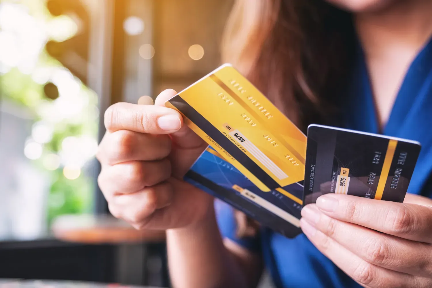 Close-up of a person holding multiple credit cards while reviewing options for a balance transfer to manage or consolidate credit card debt.