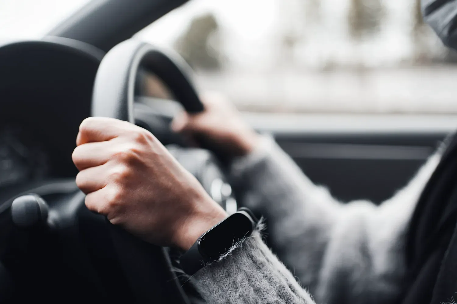 Close-up of a person’s hands on a steering wheel while driving, symbolizing finding and securing the best car loan rates for affordable financing.