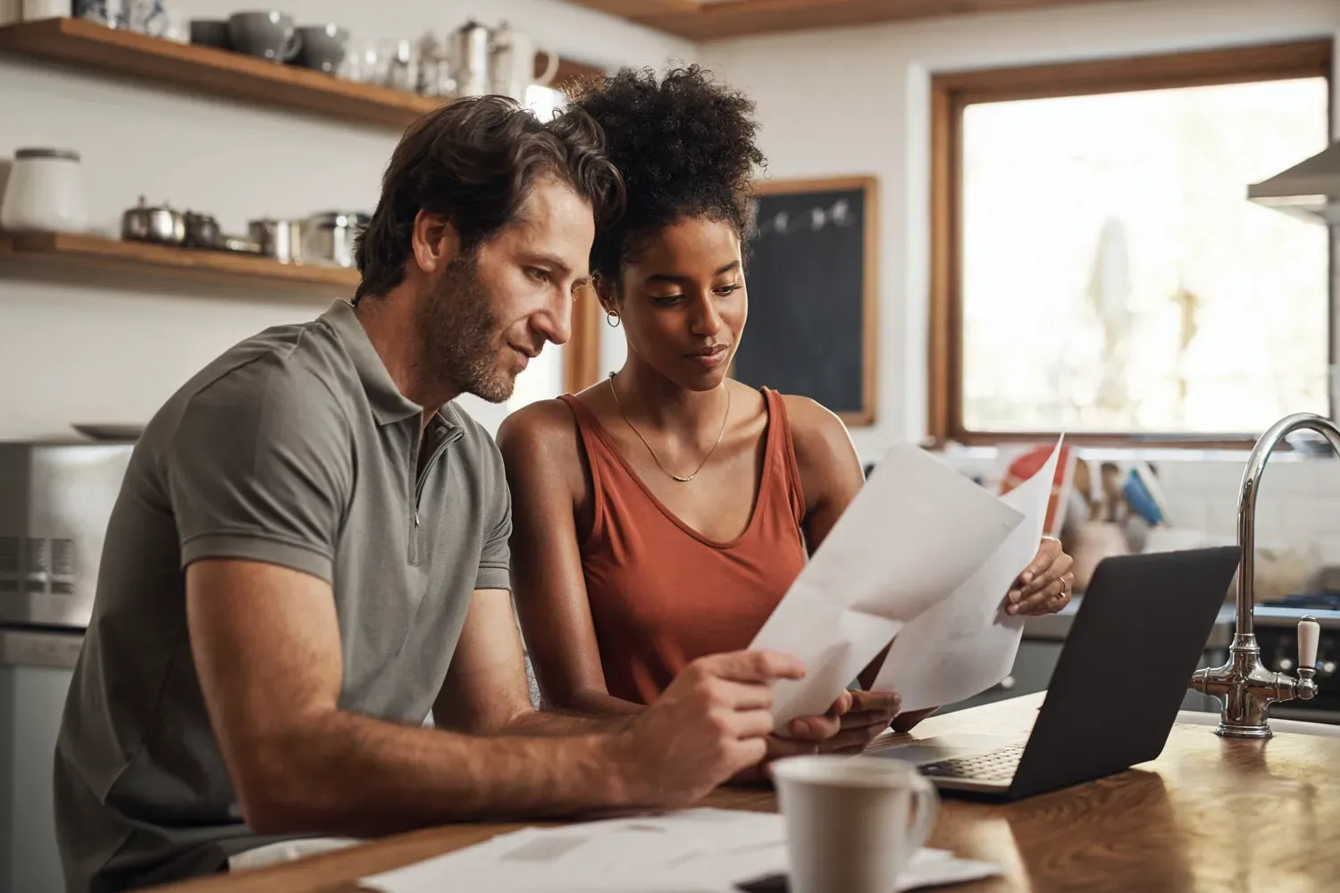 Couple sitting at a kitchen counter reviewing bills and planning how to pay off their credit card debt together.