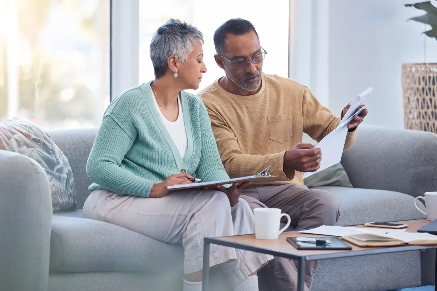 Middle-aged couple sitting on a couch reviewing financial documents together, discussing retirement planning and 401(k) options.