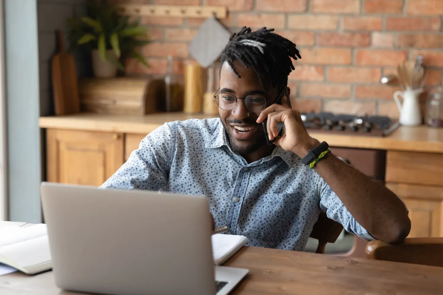 Man smiling while talking on the phone and working on a laptop, representing understanding the different types of personal loans available.