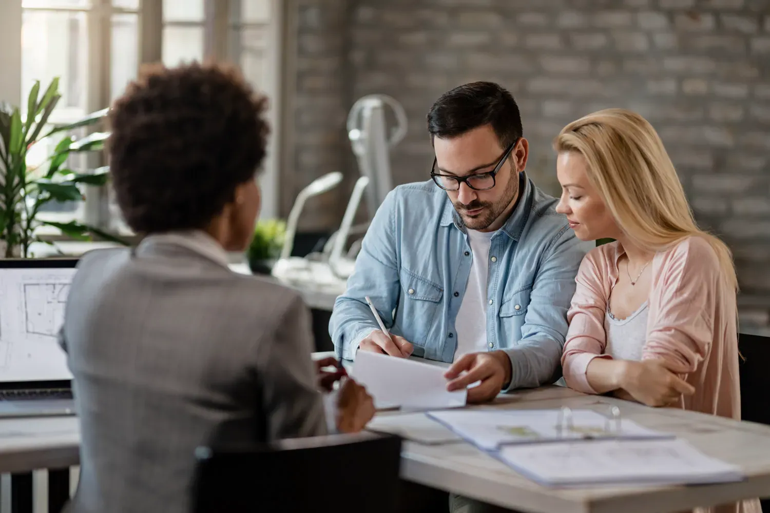 Couple reviewing loan documents with a financial advisor, representing the basics of personal loans and how they work.
